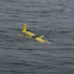 A Coastal Glider floats along the surface of the ocean.  Soon it will begin its dive through the water column, sampling the water along a saw-toothed path.  Gliders move by changing their buoyancy, without the use of a propeller. Credit: Craig Hayslip, OSU