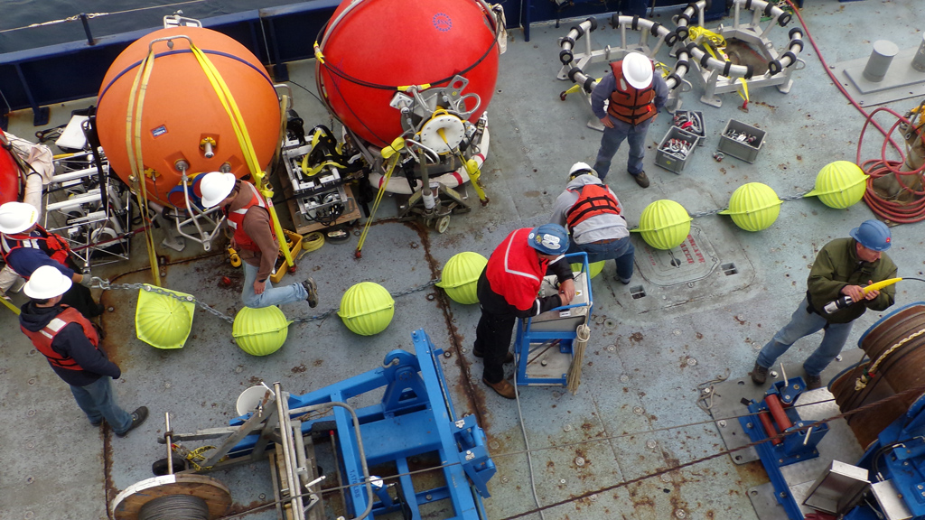 The crew preps a chain of glass balls and other mooring equipment for deployment. (Photo Credit: Bill Bergen, OOI Program Management Office)