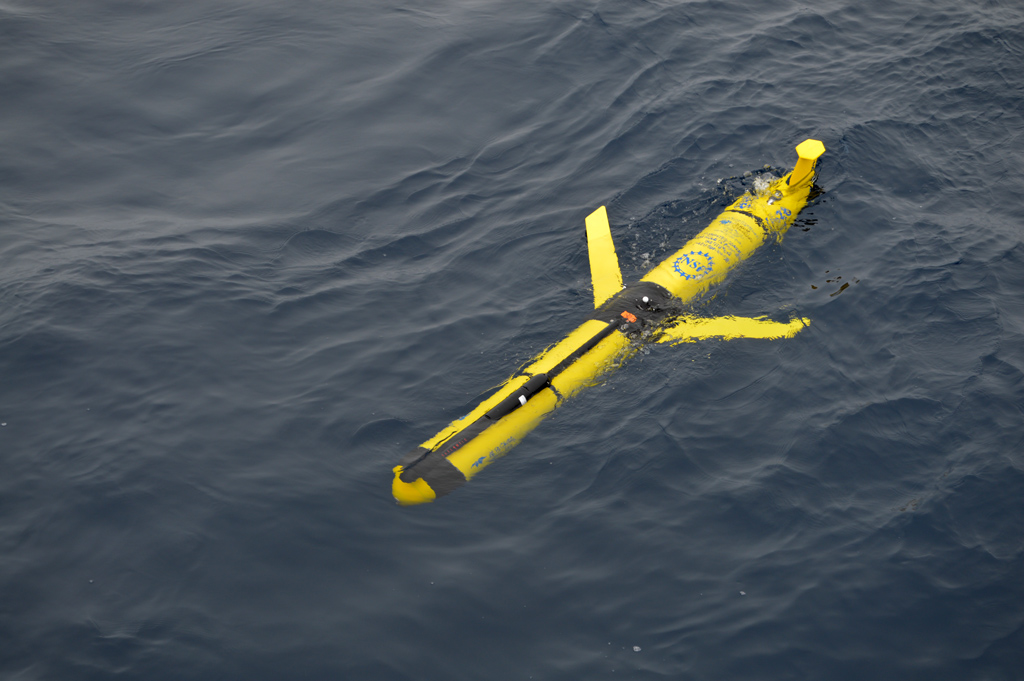 A Global Profiling Glider rests on the sea surface awaiting its first dive after deployment. These gliders, outfitted with muliti-disciplinary instruments, will remain close to the Global Profiler Mooring, and their sampling will include the region between the top of that mooring at roughly 130m depth and the sea surface. The profiling and additional three patrol gliders also have acoustic communication capabilities with the subsurface moorings and will collect their data then send it back when at the surface. (Photo Credit: Sheri N. White)