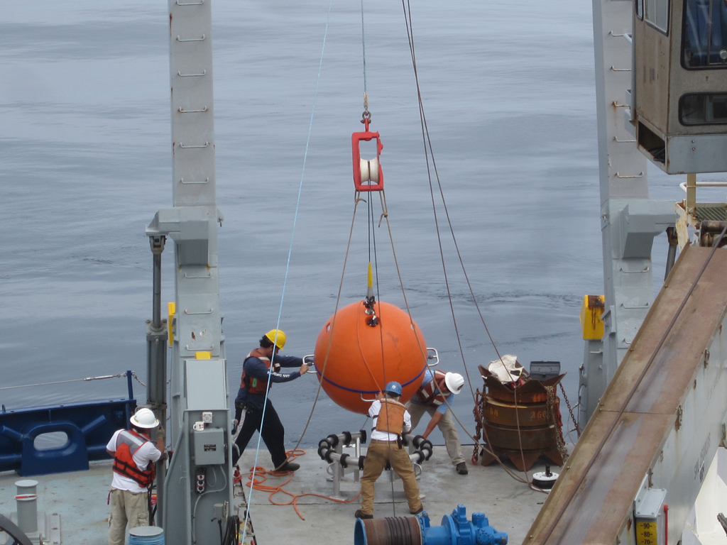 Melville "restech" Drew Cole and deck boss William Ostrom are aided by science team to deploy the main float of the Hybrid Profiler Mooring. (Photo Credit: Station Papa Science Team)